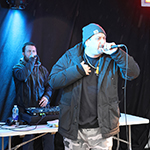 Un rappeur sur scène avec un DJ en arrière-plan.
