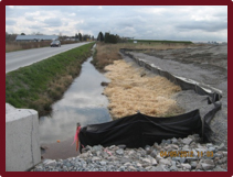 Un paillage, une clôture anti-érosion et du gravier protègent l'eau accumulée dans un fossé.